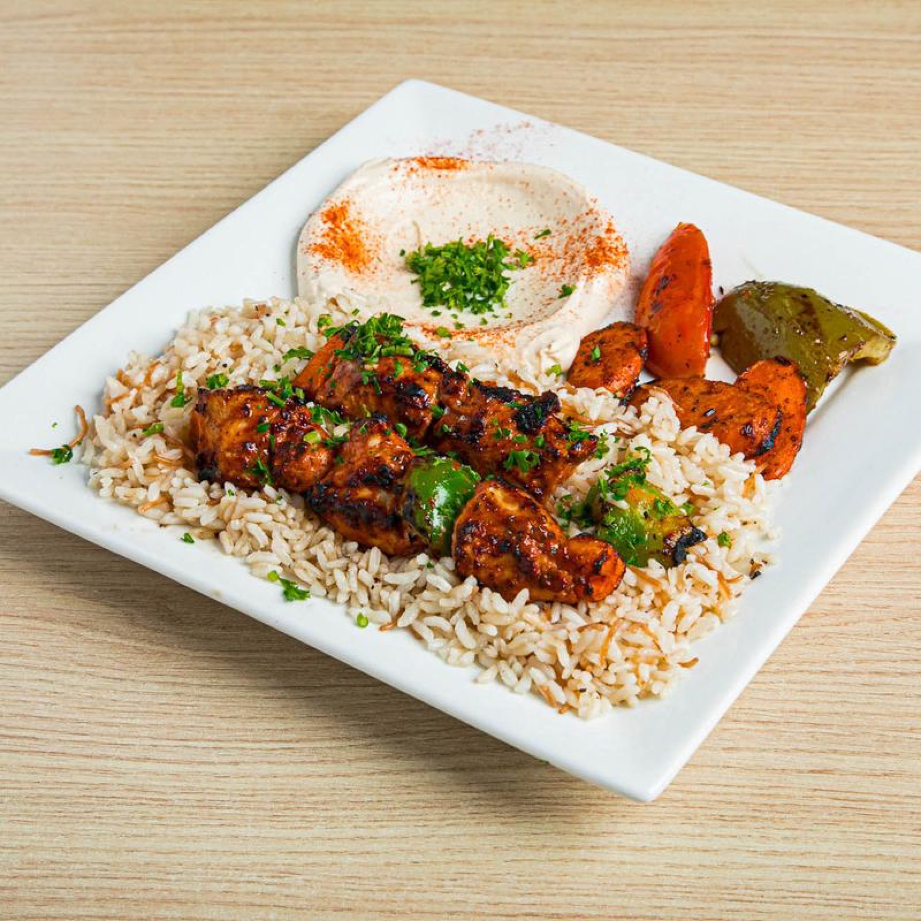 Chicken kabob over rice with hummus and grilled vegetables