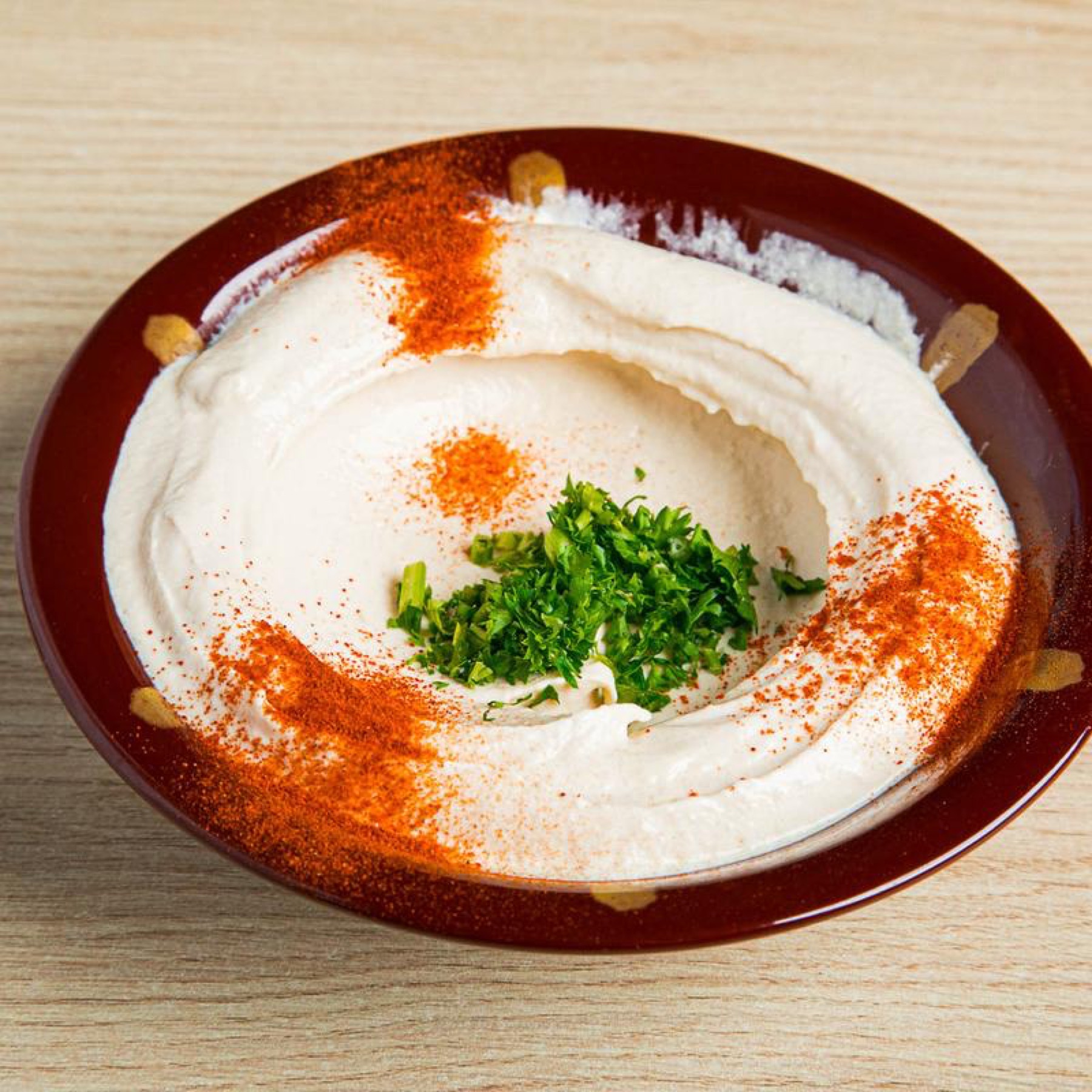 Hummus in a terracotta bowl with paprika and parsley