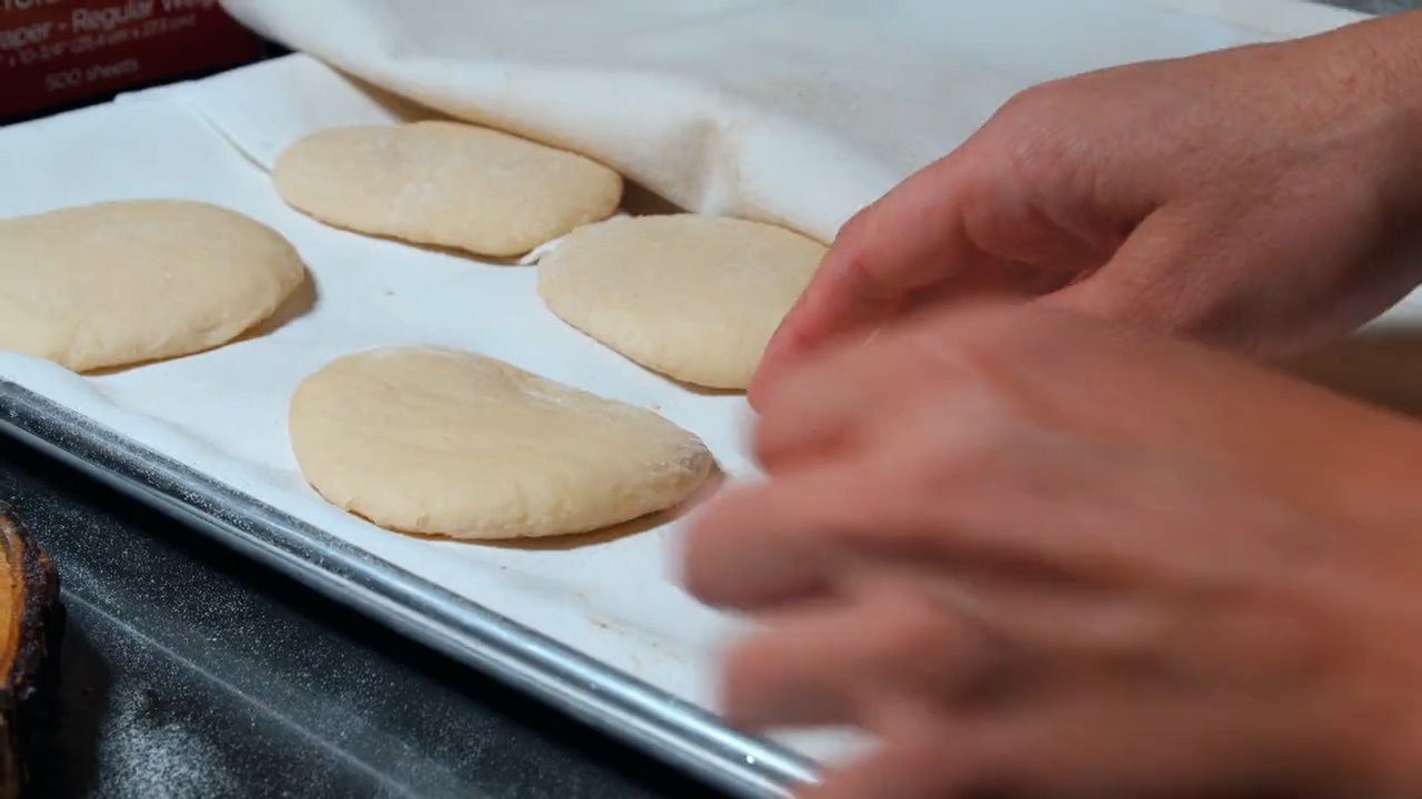 Hands laying out rounds of pita dough